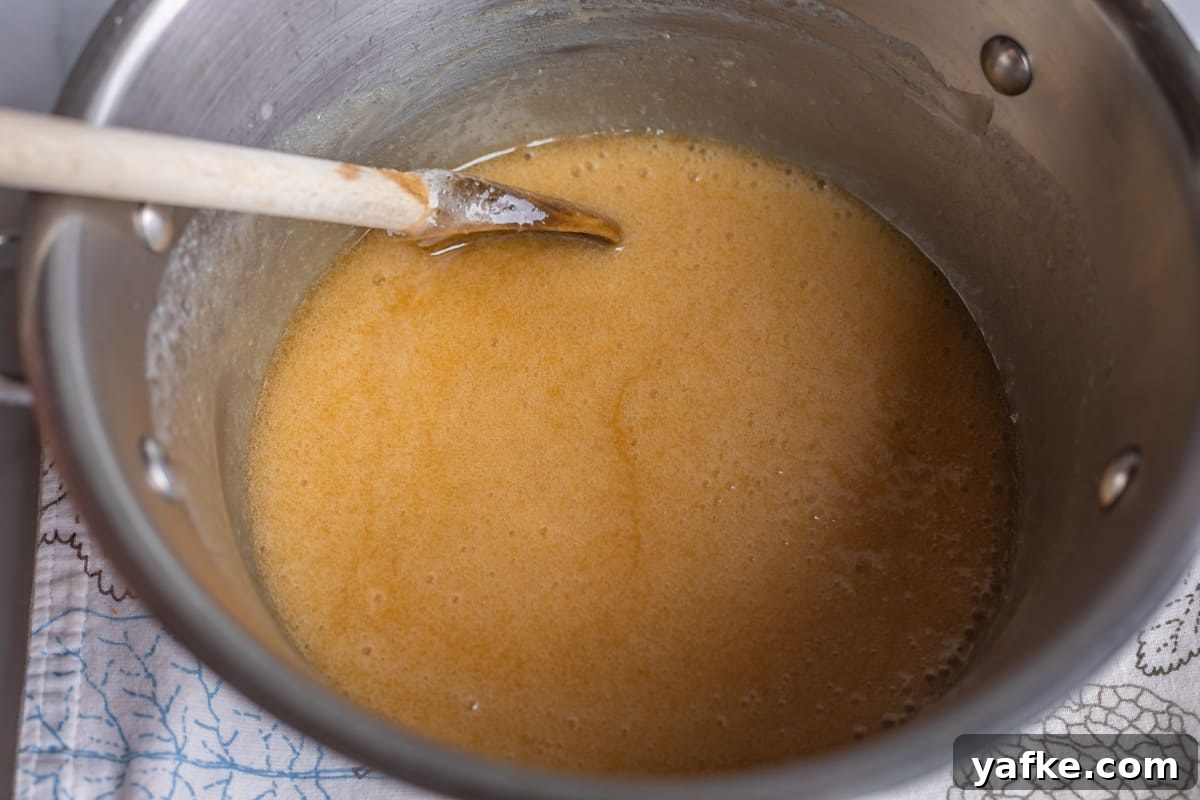 Homemade Buttermilk Syrup for Pancakes and Waffles 11 buttermilk syrup in a pot with a wooden spoon.