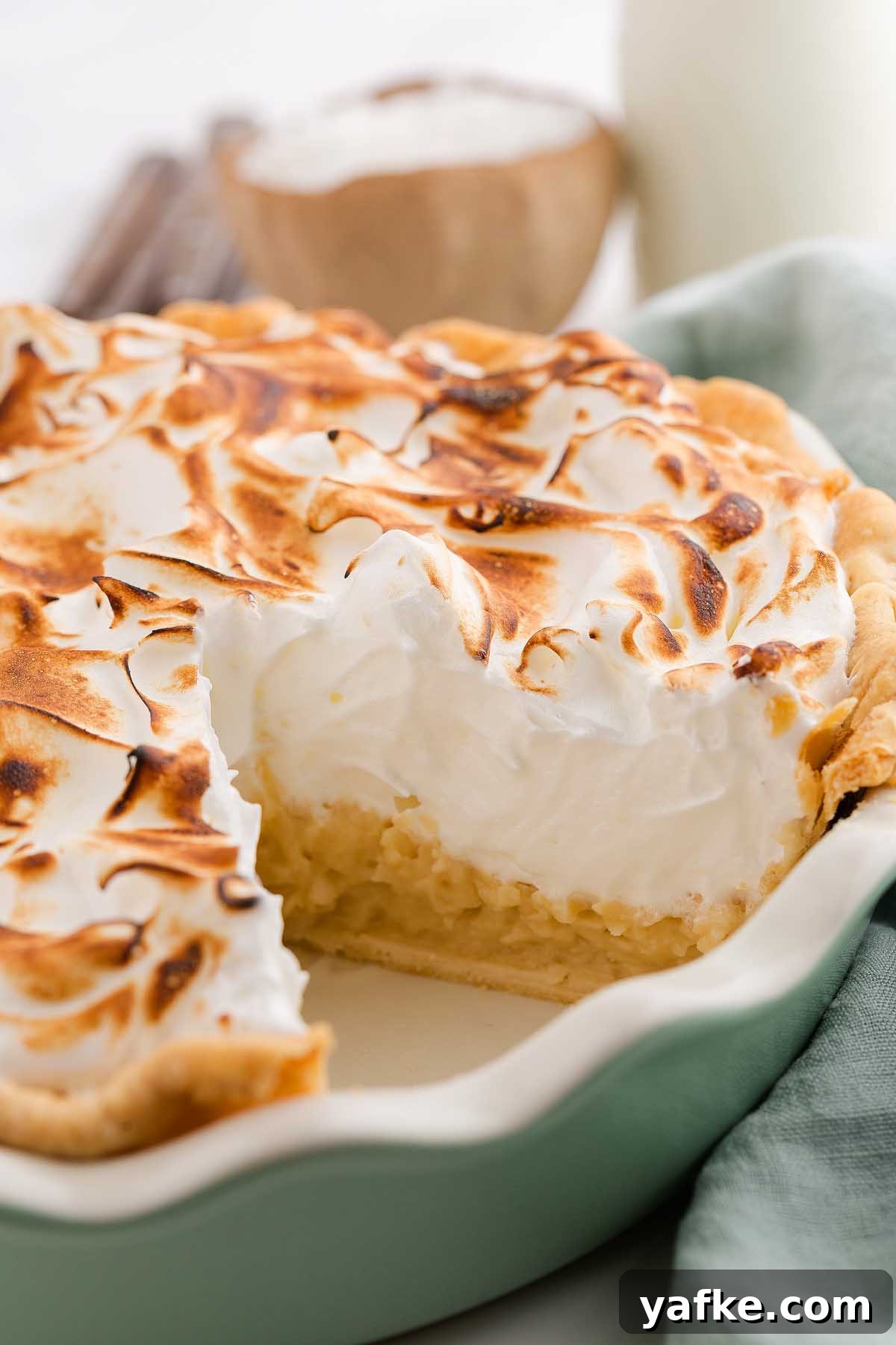 Coconut Meringue Pie with Toasted Coconut Topping 5 A creamy coconut meringue pie with a slice missing, showing off the fluffy topping and golden crust.