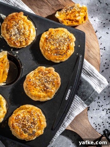 Butter chicken pies in a muffin pan on top of a wooden chopping board.