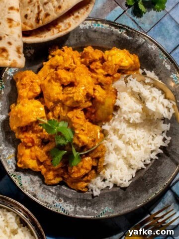Chicken karahi curry in on a plate with rice on a blue background.