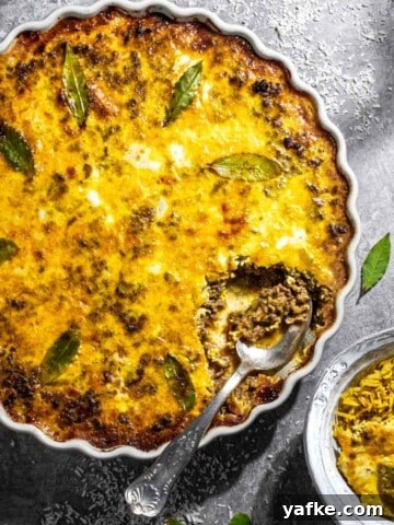 Easy South African bobotie in a white dish on a grey background.