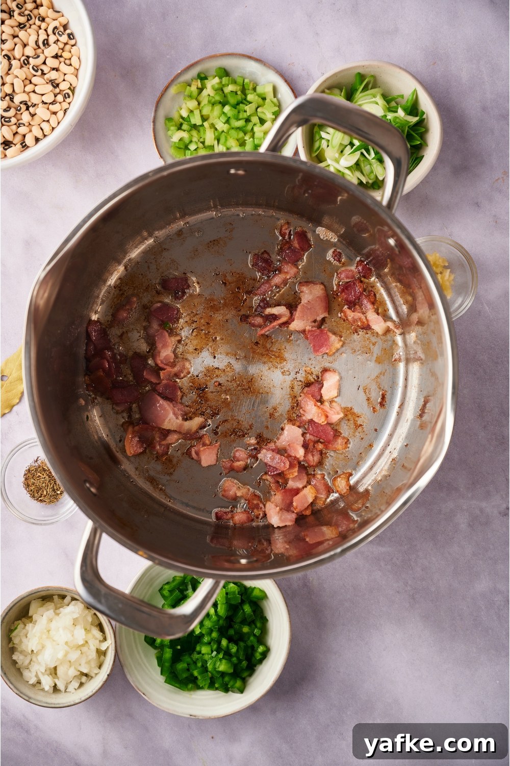 Large pot with sliced bacon cooking in the pot.