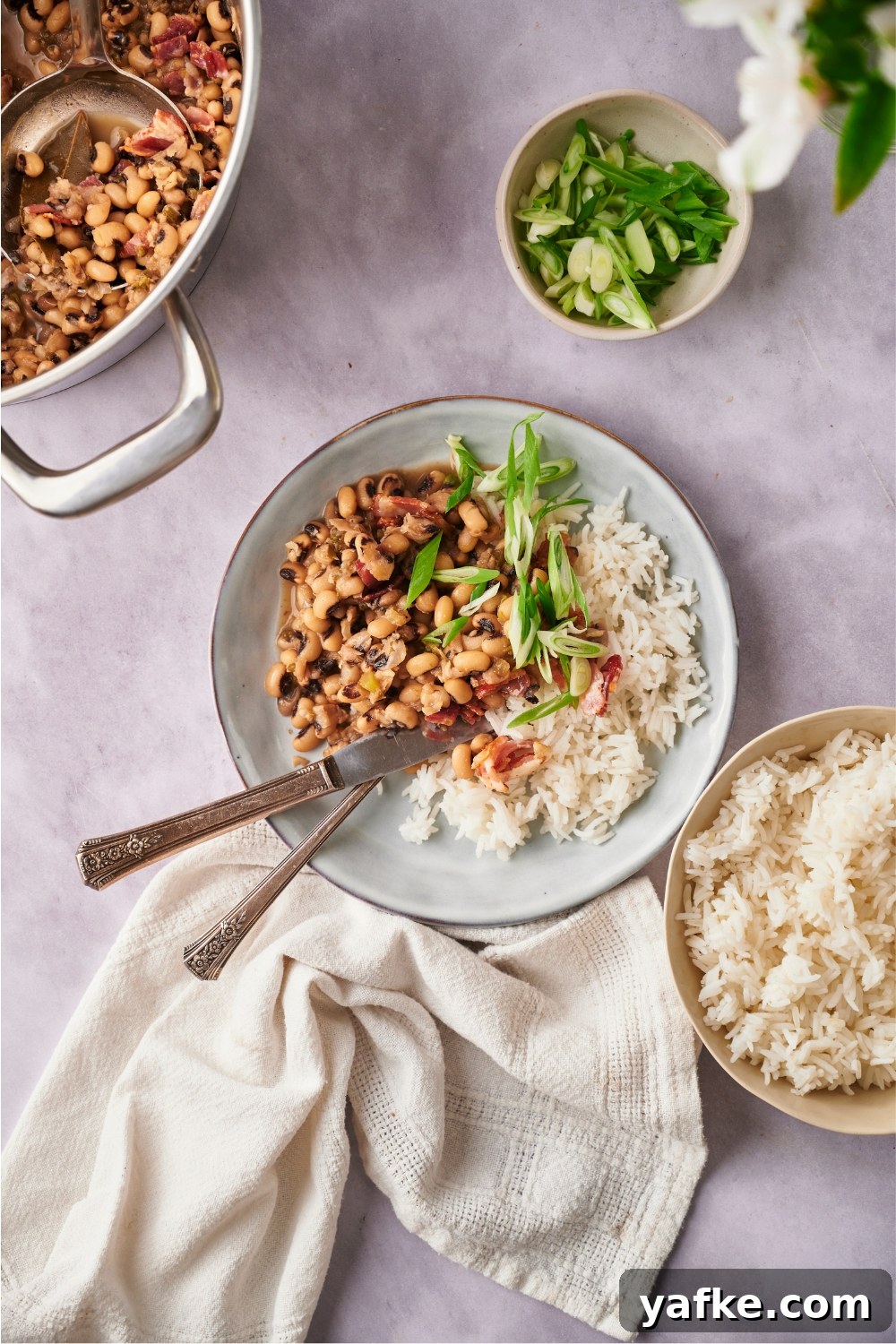 Blue bowl with a serving of hoppin' john and a fork and knife in the bowl.