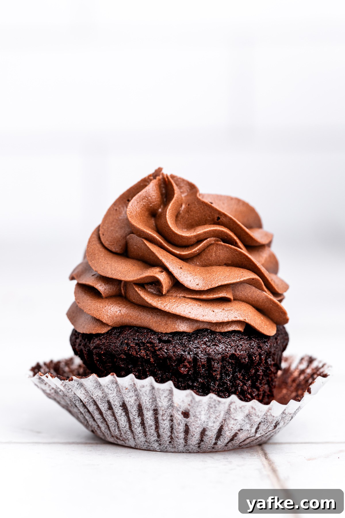Small-Batch Chocolate Cupcake Recipe 2 small batch chocolate cupcakes with chocolate frosting on a table