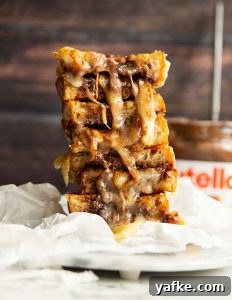 4 nutella sandwich halves stacked on each other with jar of nutella blurred in background