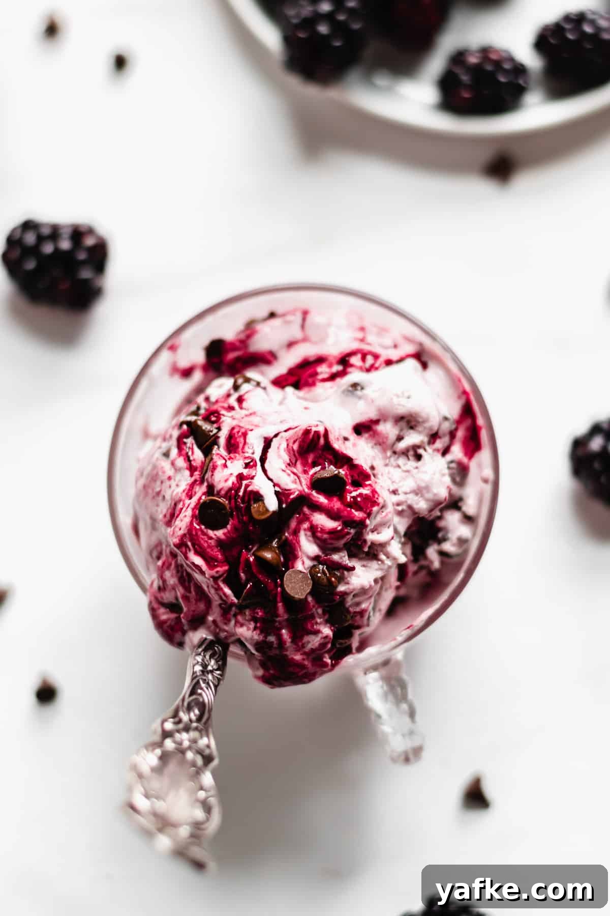 Creamy No-Churn Blackberry Chocolate Chip Ice Cream Recipe 2 Overhead shot of a cup filled with Blackberry Chip Ice Cream. A spoon sticks out.