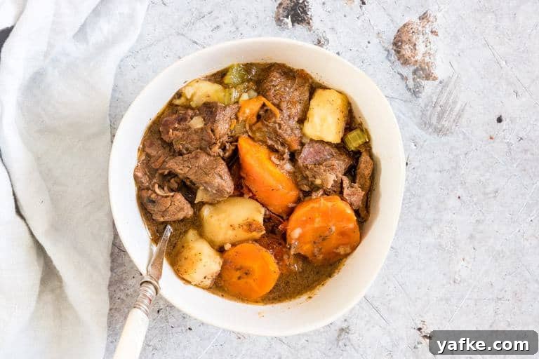 Dump-and-Start Instant Pot Beef Stew 6 Pressure Cooker Beef Stew recipe in a bowl with a spoon and cloth next to it
