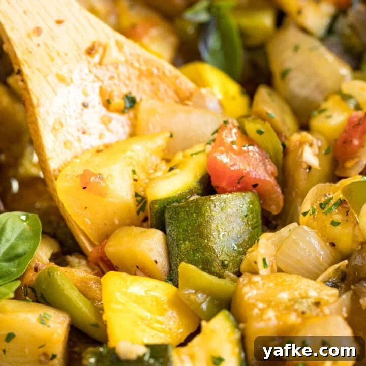 A close up of a wooden spoon in a pan of Ratatouille.