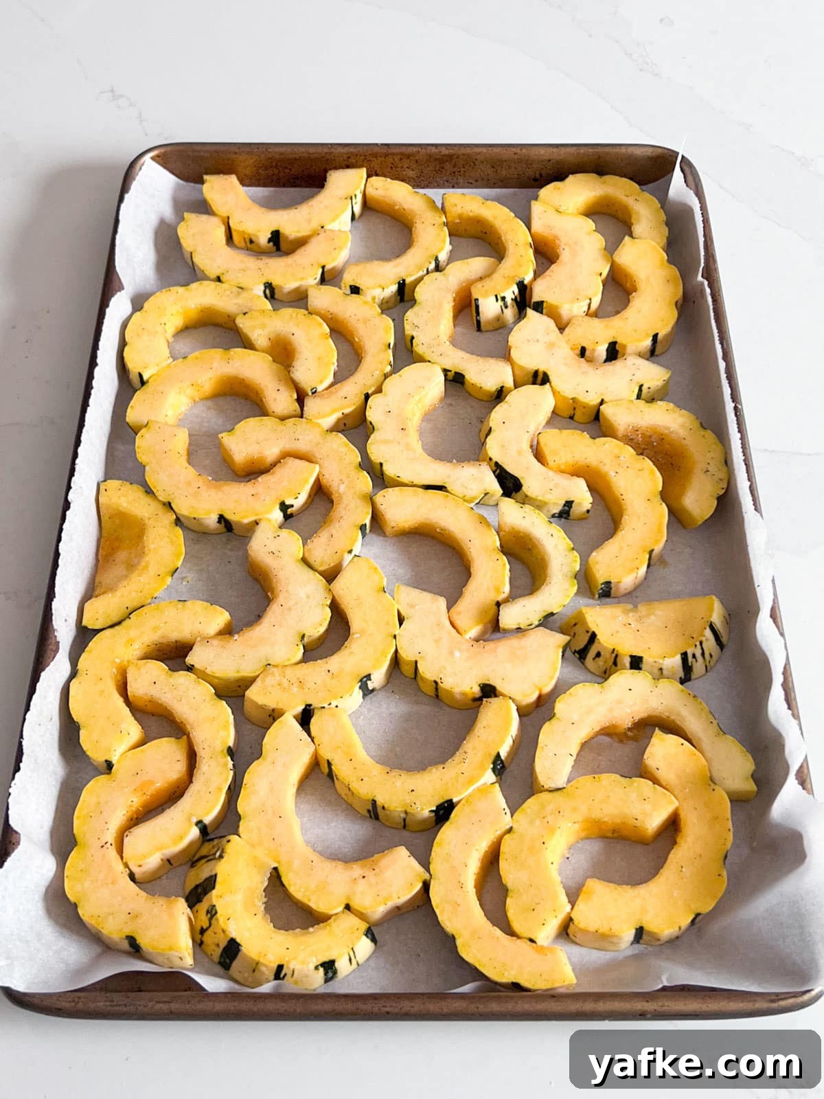 Roasted Delicata Squash with Herbed Yogurt Recipe 7 Delicata squash slices in a single layer on a parchment-lined sheet pan.