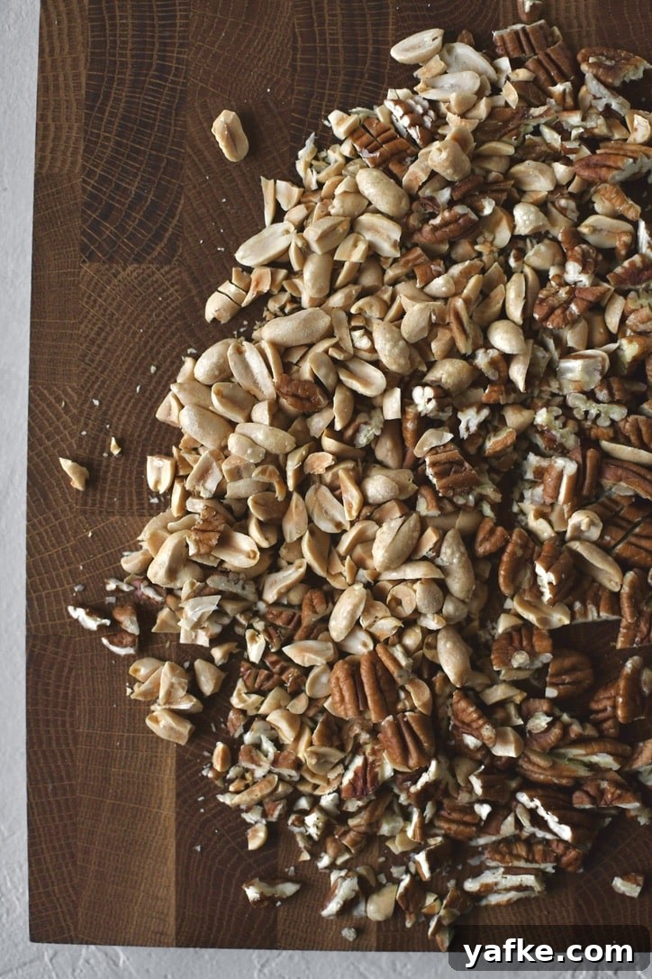 Chopped peanuts and pecans on a cutting board.
