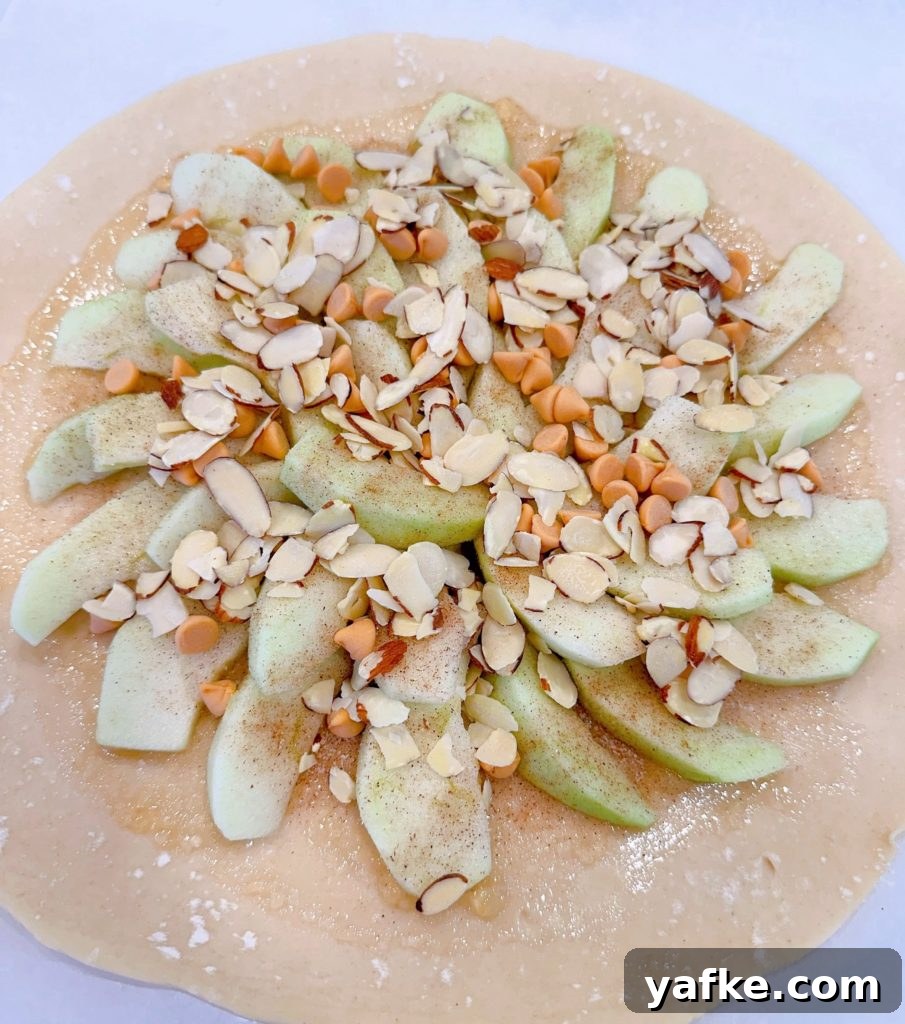 Rustic Apple Almond Galette Recipe with Flaky Crust 9 almonds and baking chips sprinkled on top of the apple pie filling.