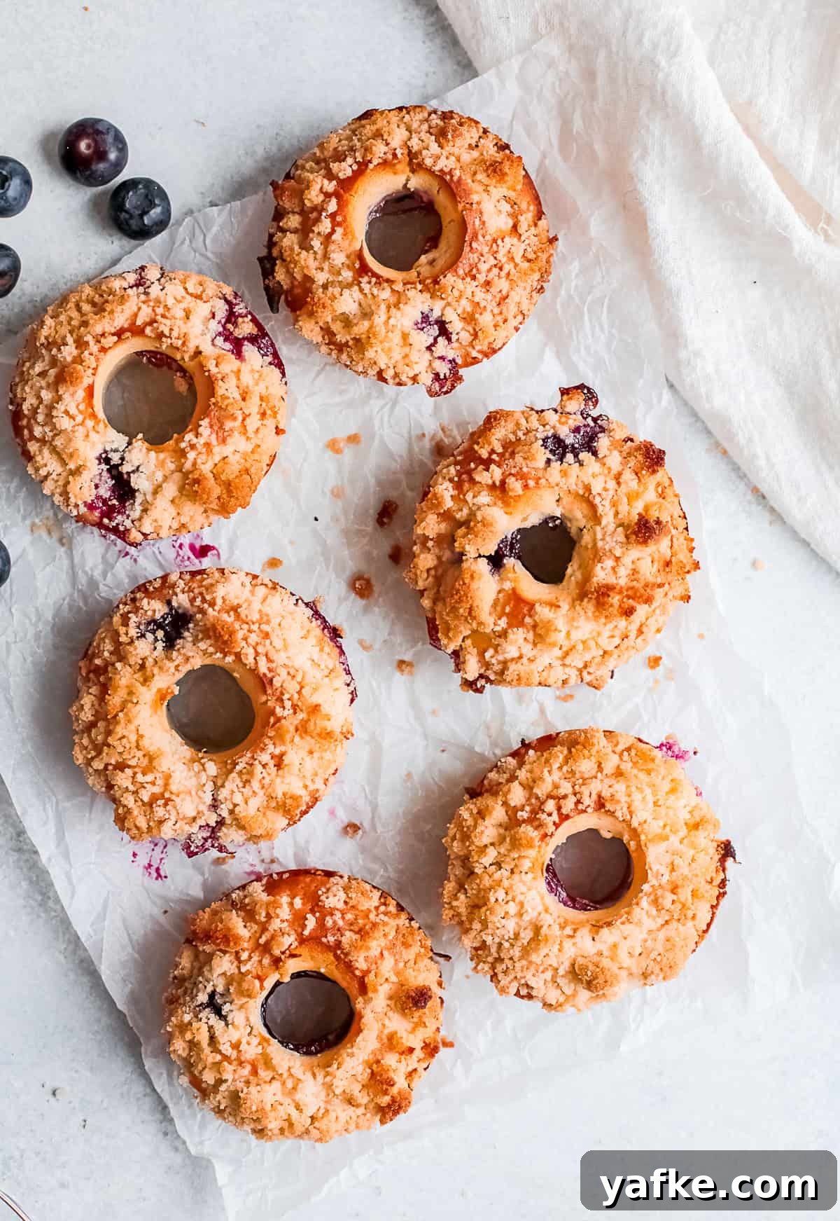 Oven-Baked Blueberry Streusel Donuts Recipe 8 Baked Blueberry Streusel Donuts served on a table.