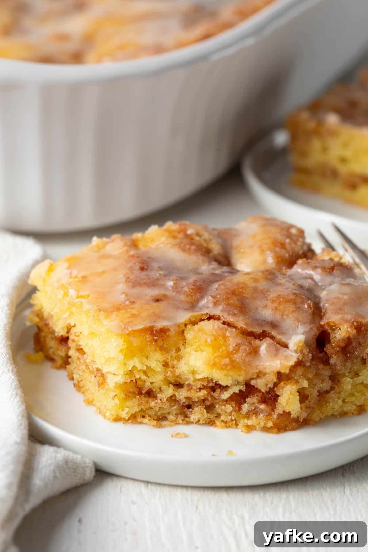 slice of honey bun cake with a bite taken out.