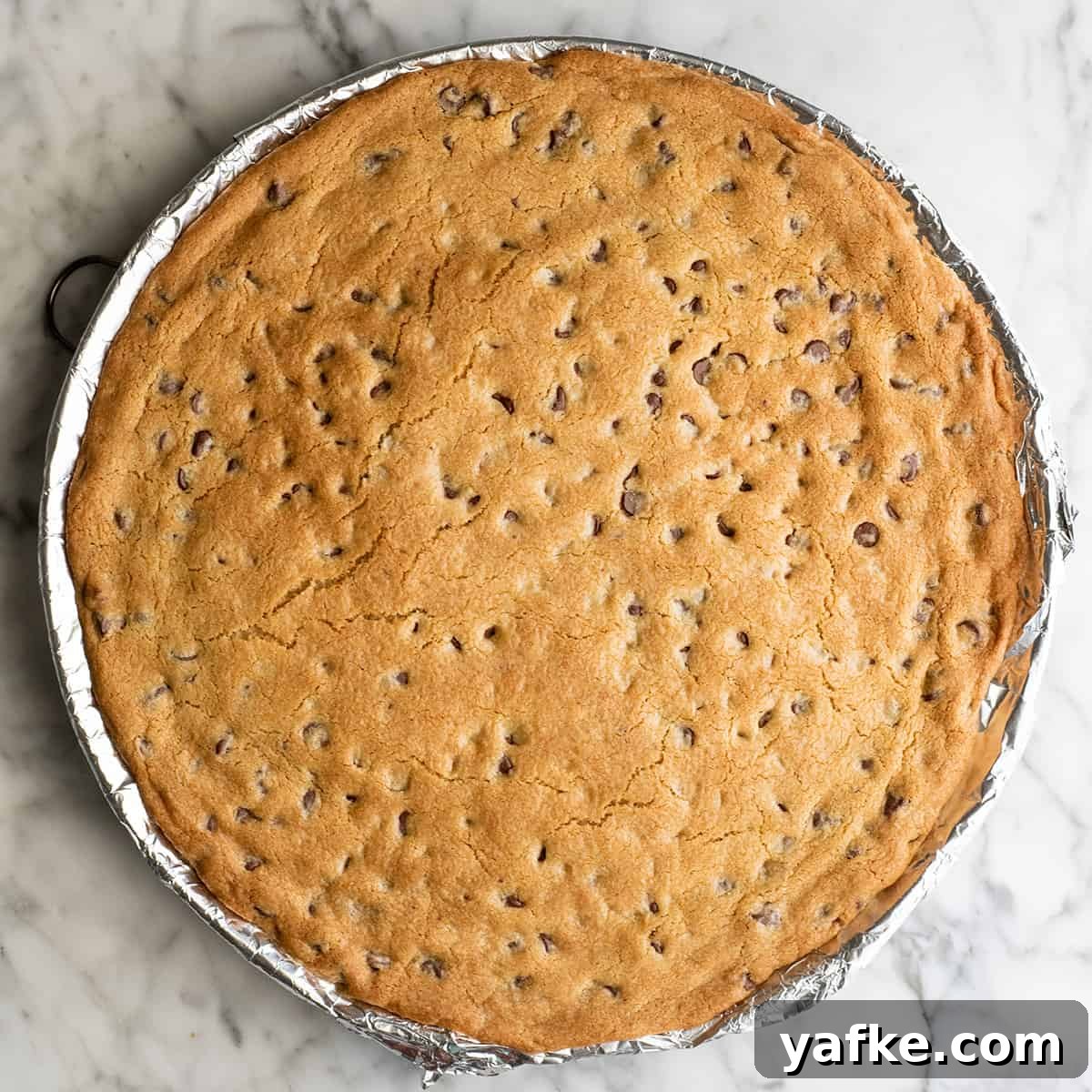 chocolate chip cookie cake on a baking sheet after baking