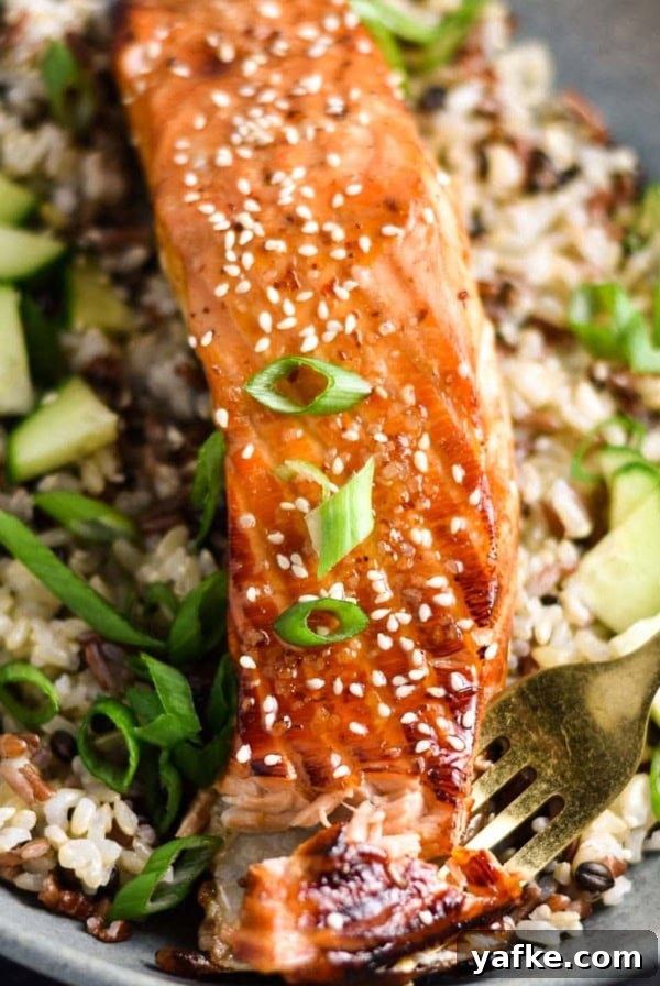 A fork in a fillet of salmon topped with sweet chili sauce.