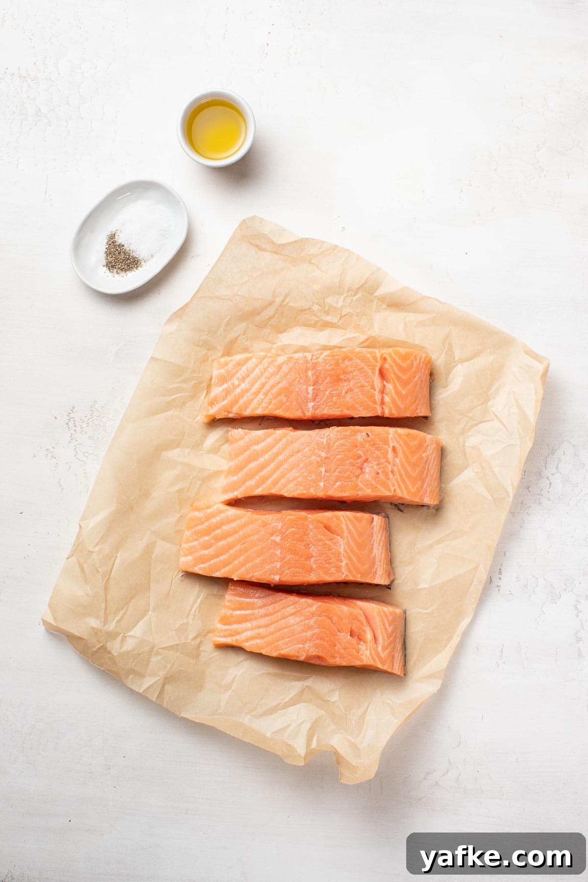 Pan-Seared Salmon with Crispy Skin and Lemon Butter Sauce 3 Salmon fillets, salt and pepper, and olive oil on a white background.