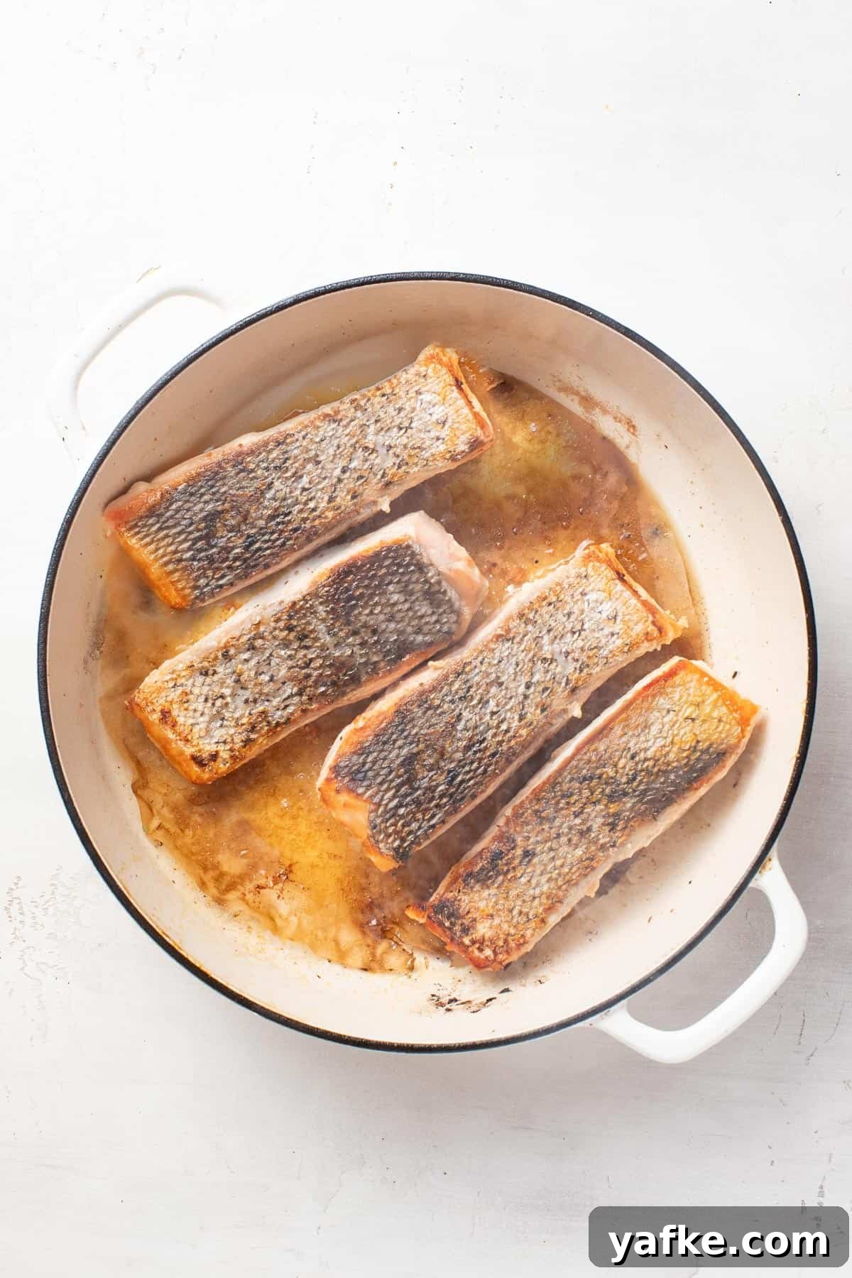 Pan-Seared Salmon with Crispy Skin and Lemon Butter Sauce 7 Salmon with the seared skin on top in a pan.