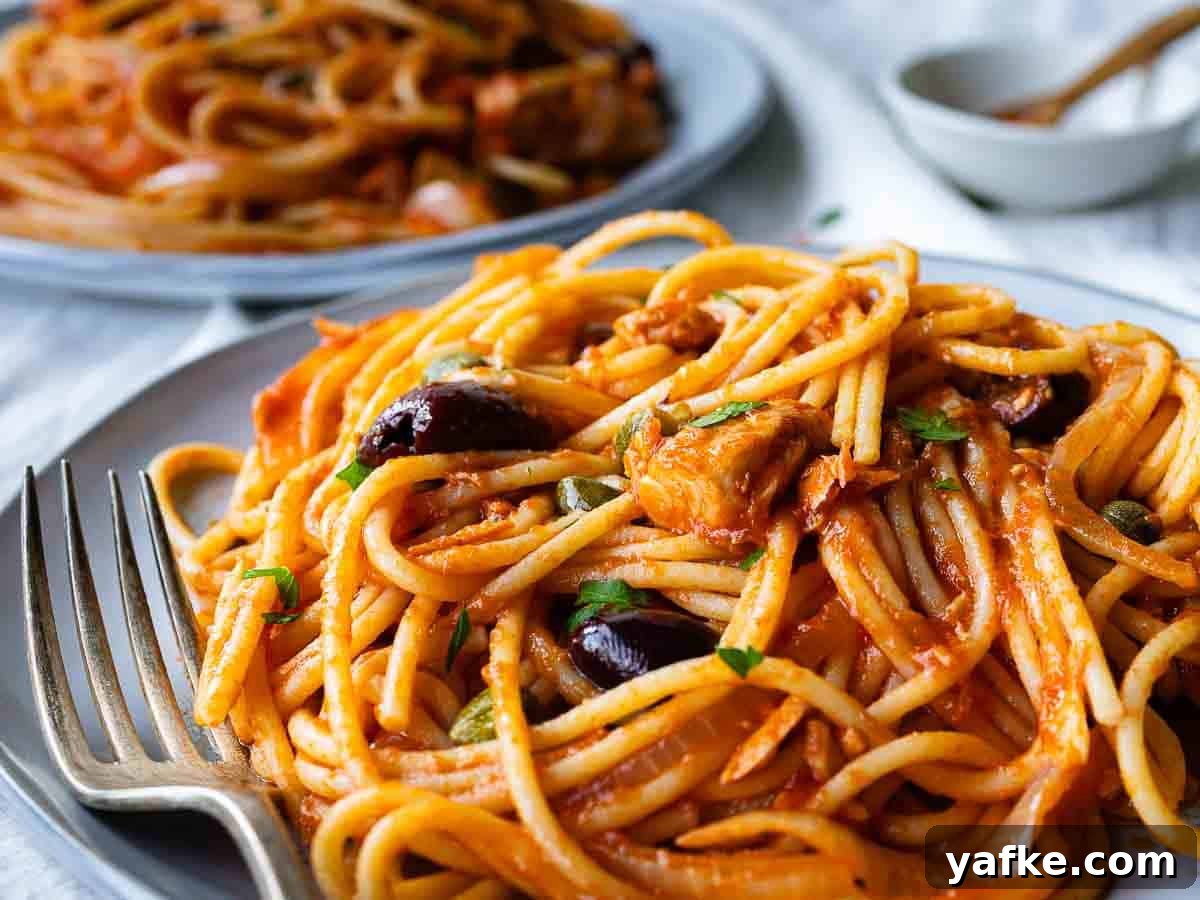 Creamy Tuna Pasta Recipe with Lemon & Capers 5 Close up of a plate of spaghetti with a tuna and tomato sauce.