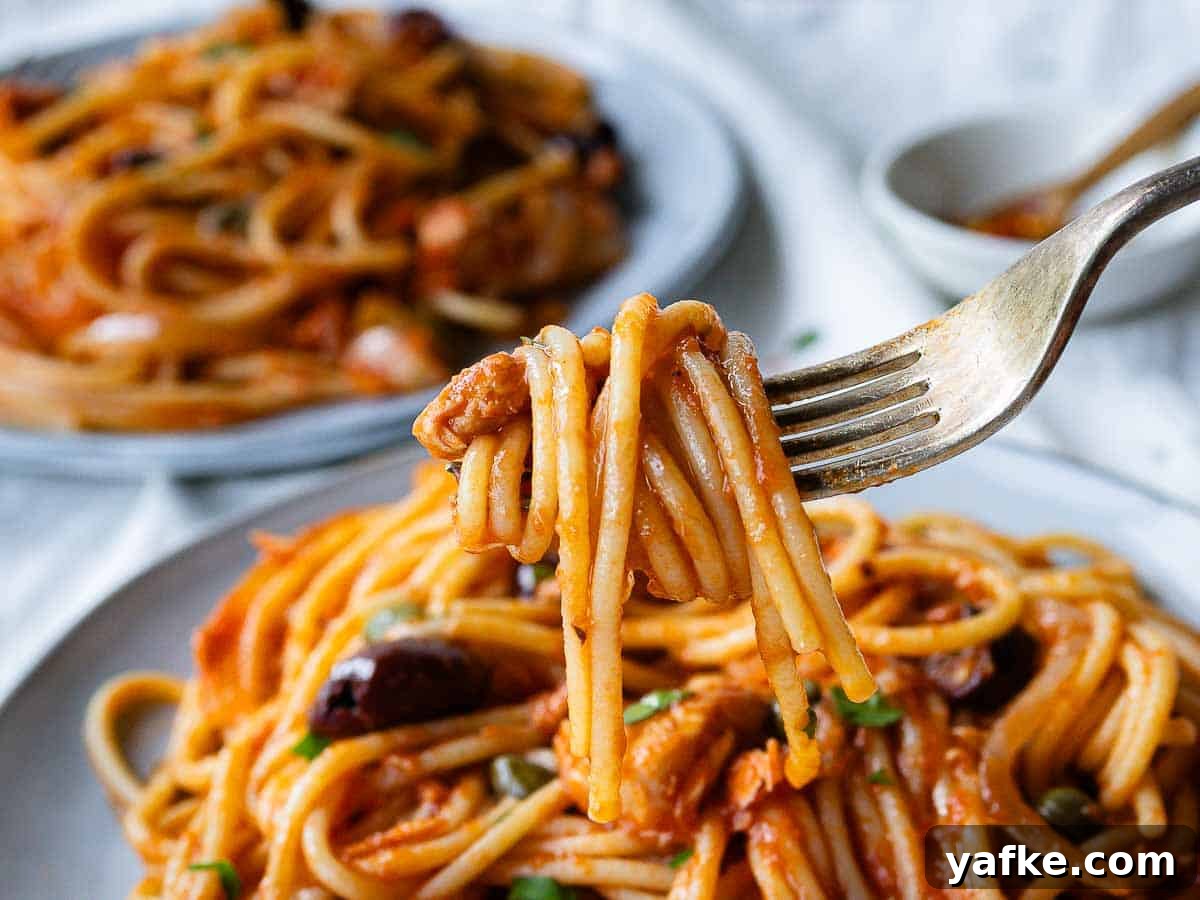 Creamy Tuna Pasta Recipe with Lemon & Capers 6 Tuna Spaghetti twisted around a fork above a plate of spaghetti.