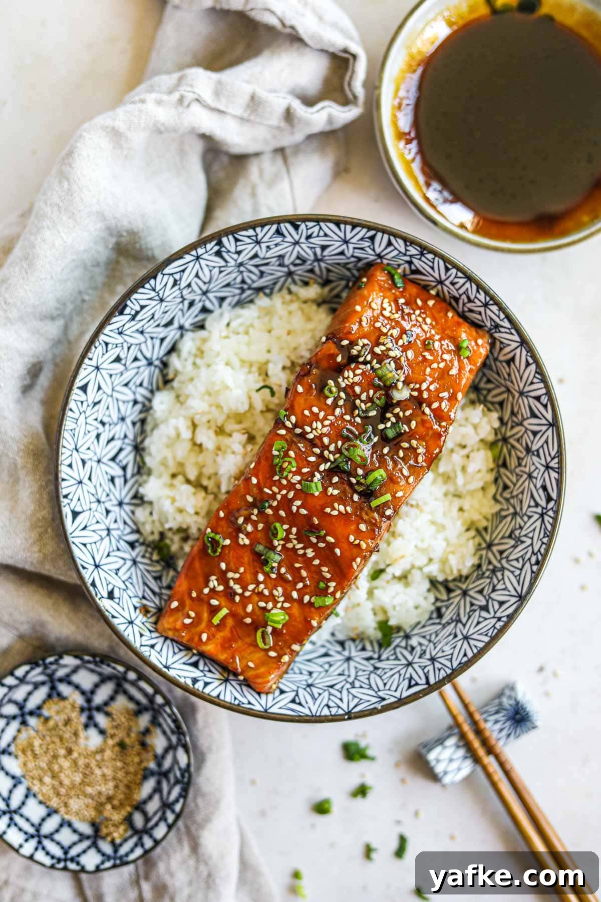 Teriyaki Salmon Donburi: Classic Japanese Rice Bowl 6 Teriyaki salmon donburi with sesame seeds, teriyaki sauce, green onion, and chopsticks.
