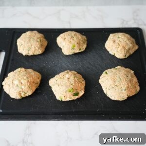 Crispy Salmon Croquettes Recipe with Lemon Dill Sauce 6 Salmon patties formed on a cutting board.
