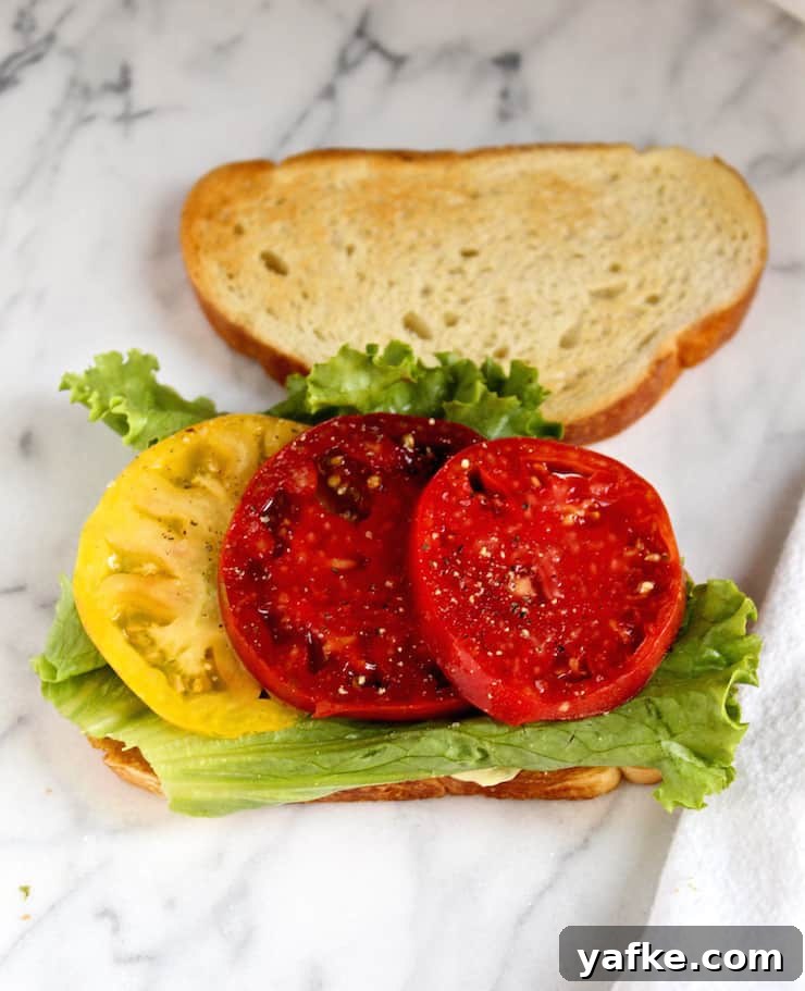 Avocado and Pesto Mayonnaise BLT Recipe 7 Open faced start of BLT with tomato and lettuce.