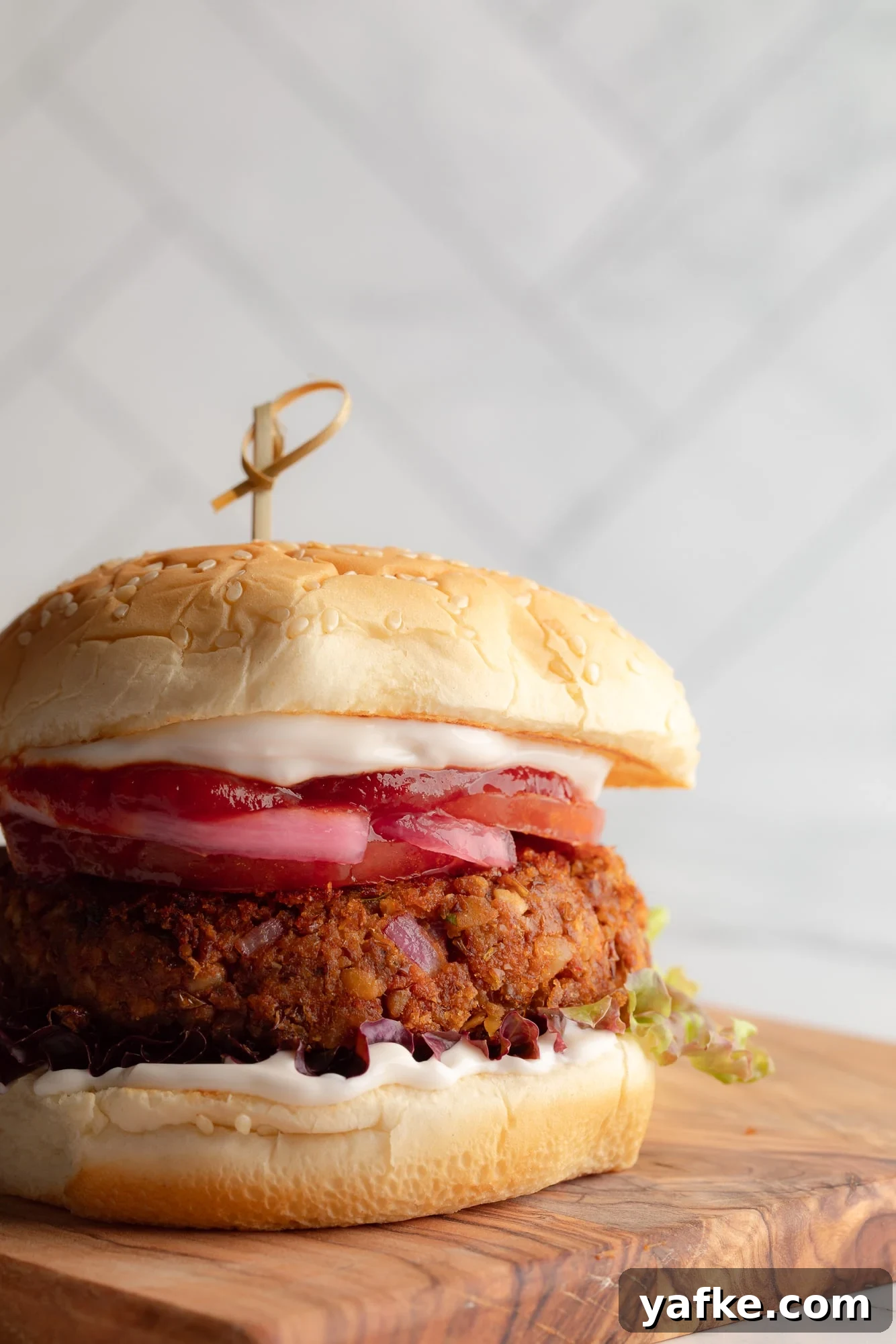 Vegan Lentil Burgers with Garlic and Herbs 3 side view of a lentil burger on a bun topped with vegan mayo and ketchup.