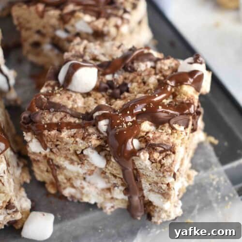 smores rice krispie treat sitting on edge of pan with chocolate dripping off edge