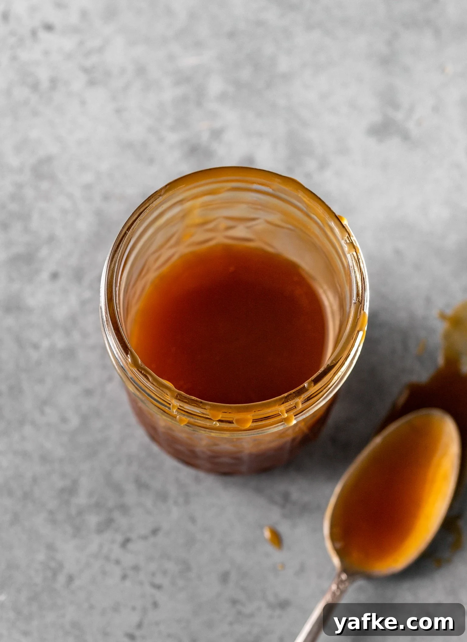 How to Make No Churn Bourbon Salted Caramel Ice Cream 3 Bourbon salted caramel inside of a mason jar with a caramel-covered spoon nearby