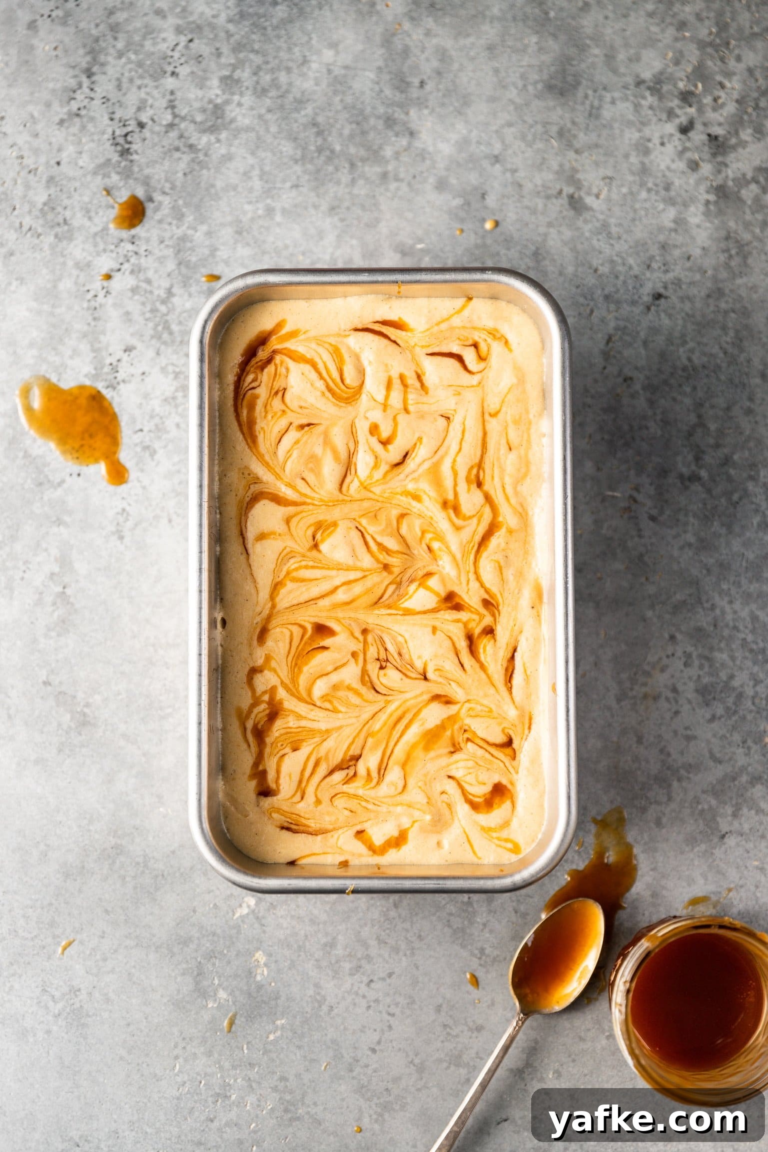 How to Make No Churn Bourbon Salted Caramel Ice Cream 5 No Churn Bourbon Salted Caramel Ice Cream with caramel swirled on top inside of a loaf pan