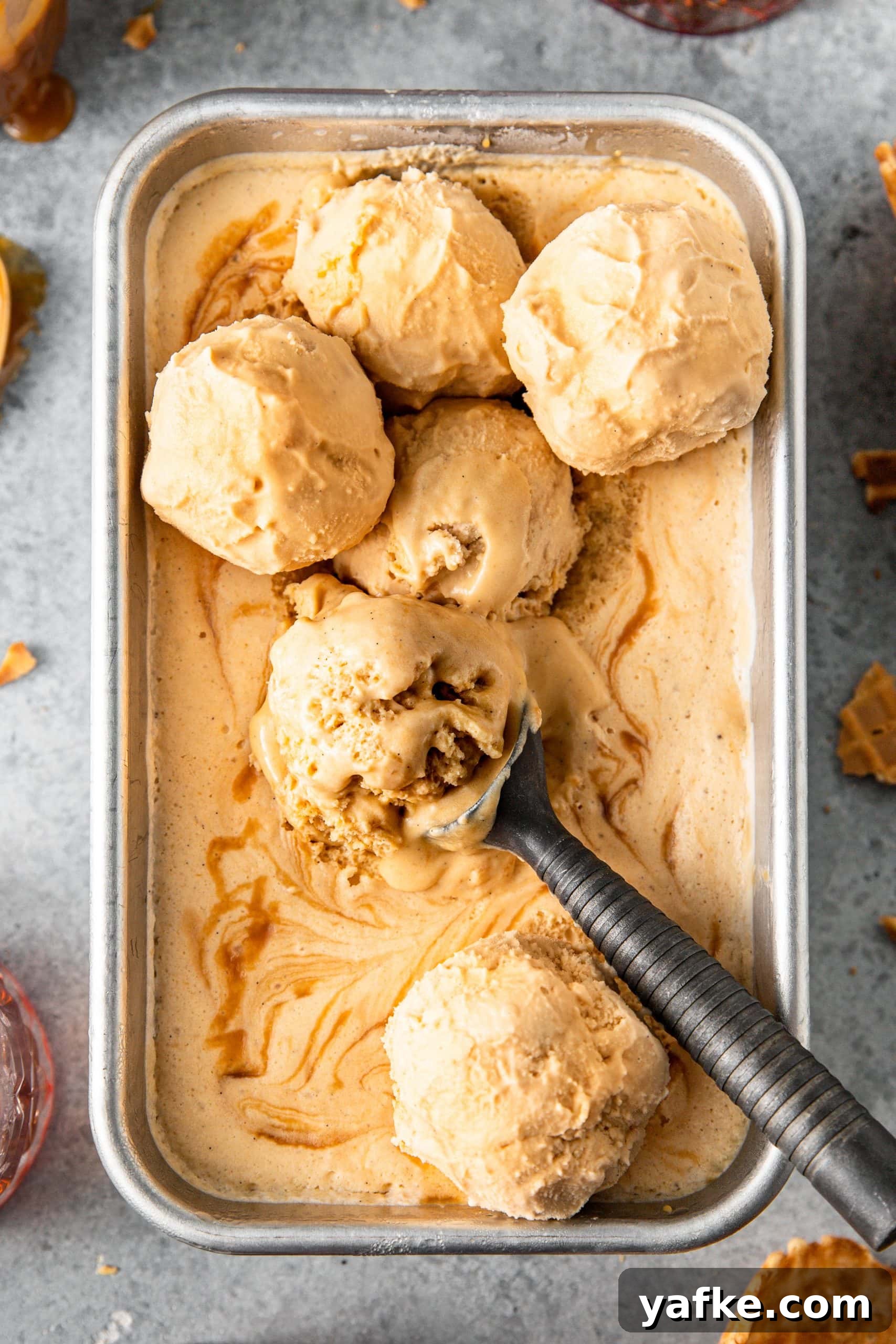 How to Make No Churn Bourbon Salted Caramel Ice Cream 7 Scoops of No-Churn Bourbon Salted Caramel Ice Cream on top of the ice cream in a loaf pan.