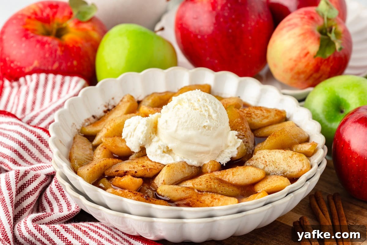 Skillet Fried Apples with Cinnamon and Brown Sugar 6 Fried apples in a white dish, topped with vanilla ice cream; apples and striped towel behind.