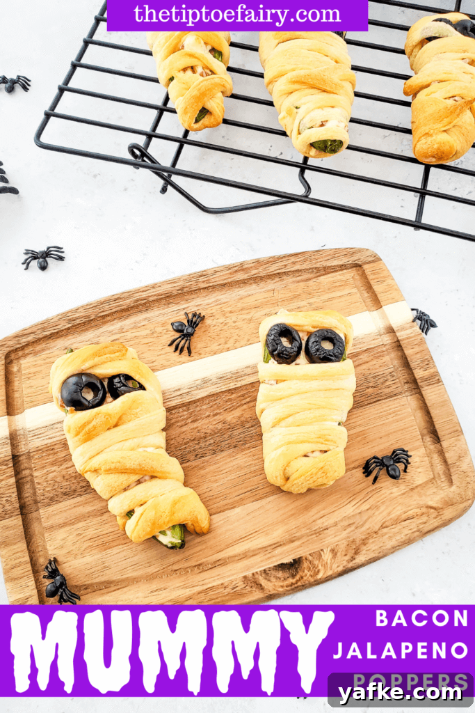 Halloween Bacon-Wrapped Mummy Jalapeno Poppers Recipe 2 title image of mummy bacon jalapeno poppers on a wooden cutting board with plastic spiders around them.