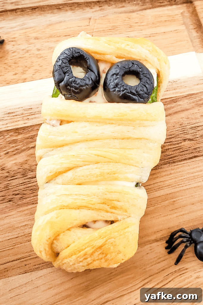 Halloween Bacon-Wrapped Mummy Jalapeno Poppers Recipe 8 A close up image of a single Mummy Bacon Jalapeno Popper