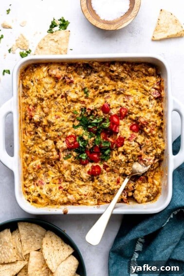 Creamy White Queso Dip Recipe for Tacos and Chips 10 White baking dish filled with baked rotel dip topped with cilantro and chopped tomatoes.
