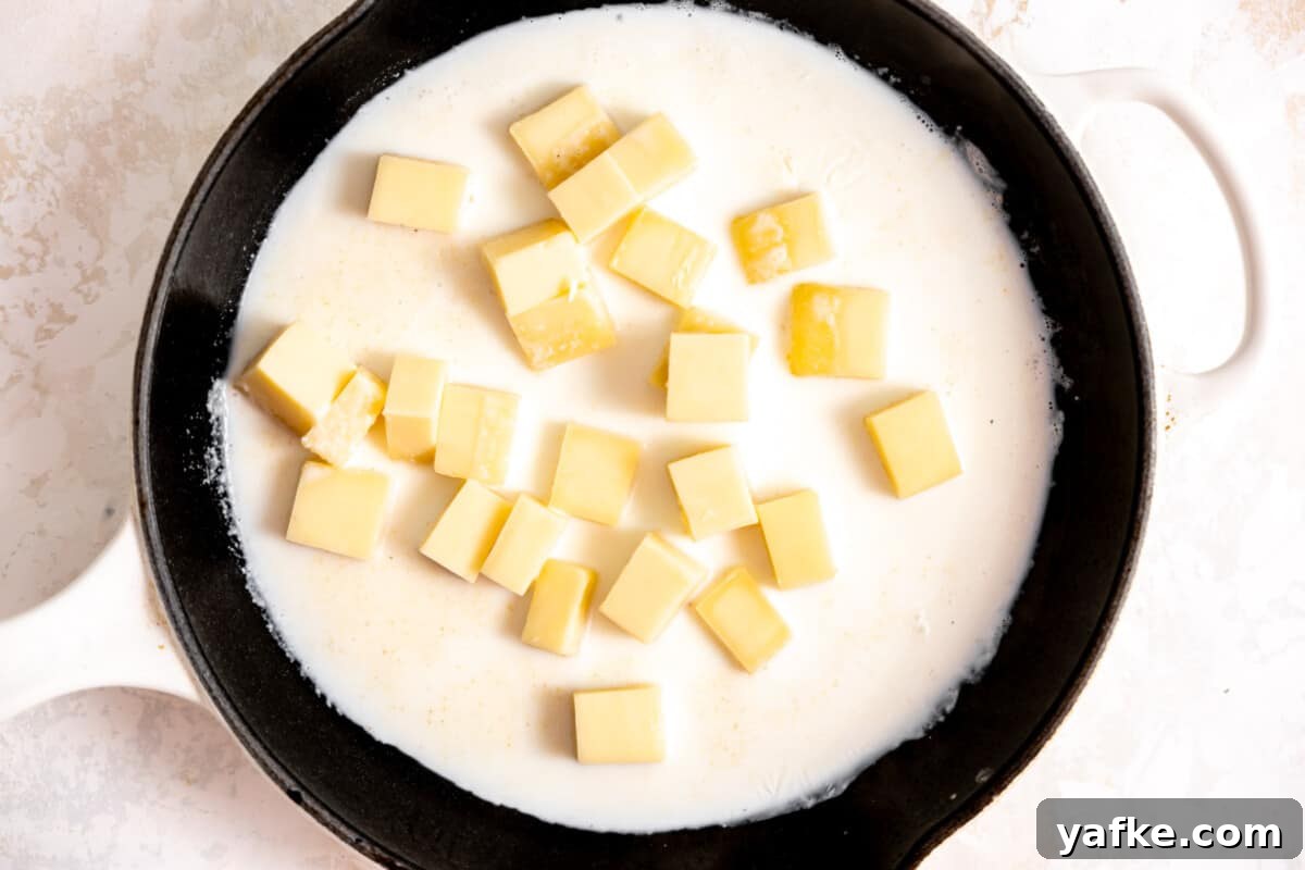 Creamy White Queso Dip Recipe for Tacos and Chips 4 Skillet with cream and chunks of white American cheese melting.
