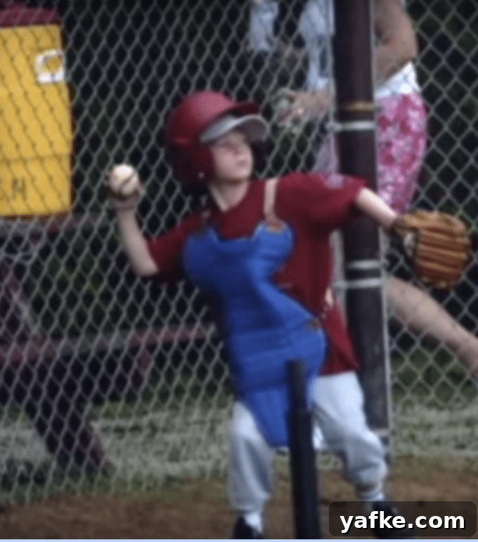 A young boy throwing a baseball with a catcher's equipment on.