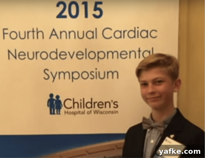 A young boy in a suit standing in front of sign.