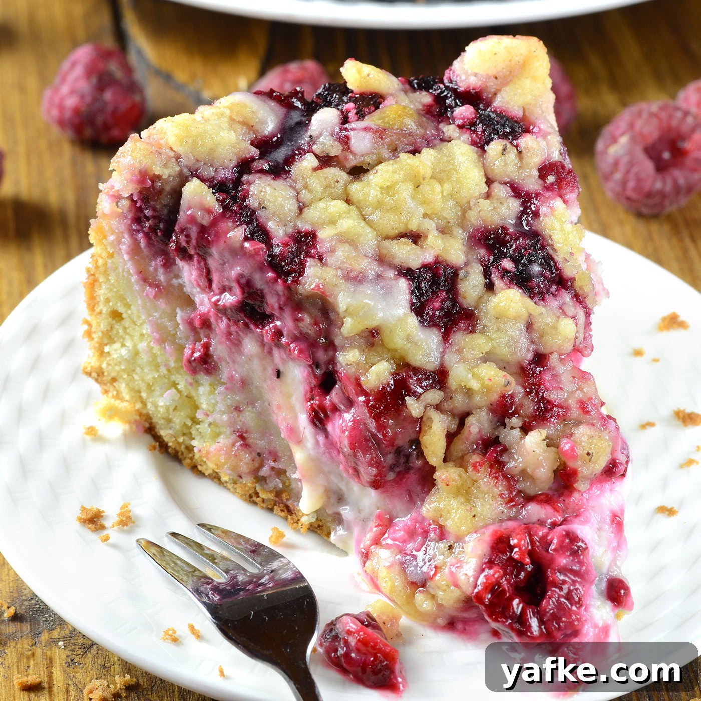 close up of raspberry cream cheese coffee cake slice with streusel topping and gooey raspberry filling