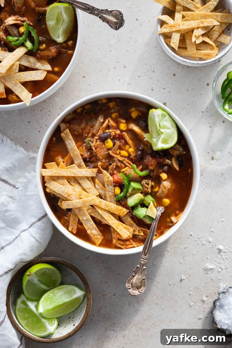 Chicken Tortilla Soup Recipe with Avocado and Lime 2 Healthy chicken tortilla soup in a white bowl with a spoon.