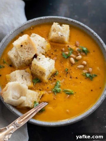 Pumpkin and Carrot Soup in a grey bowl with croutons.