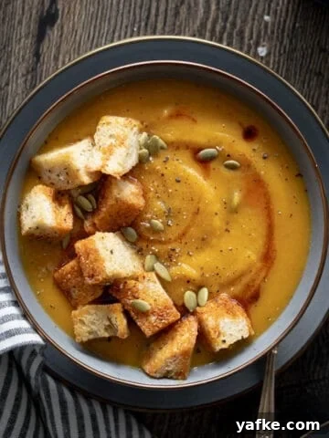 Butternut Squash and Carrot Soup in a bowl with jumbo croutons.