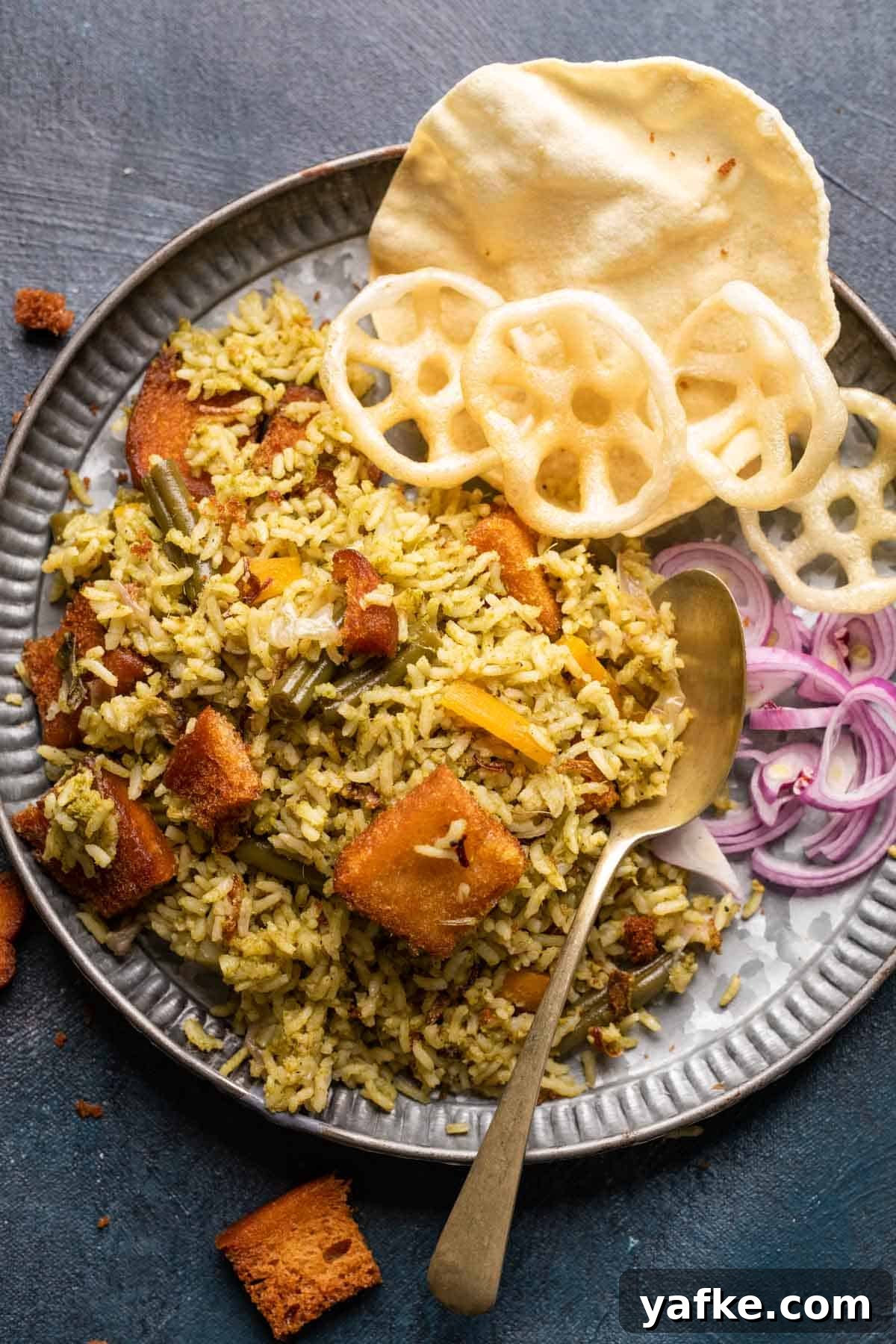 Kavitha Aunty's Traditional Rice Bath Recipe 2 Rice bath served in a grey plate with fryums, poppadum and onions on the side
