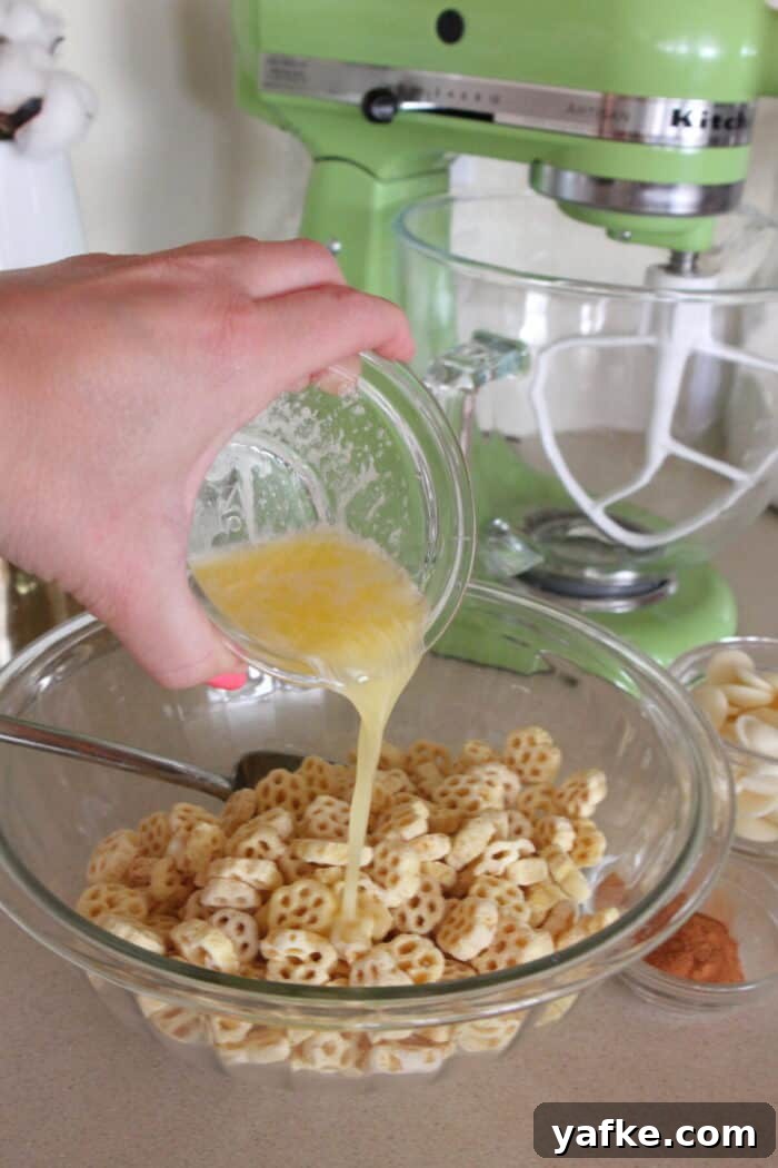 White Chocolate Churro Crunch Snack Mix Recipe 4 pouring melted butter into honey comb cereal in mixing bowl