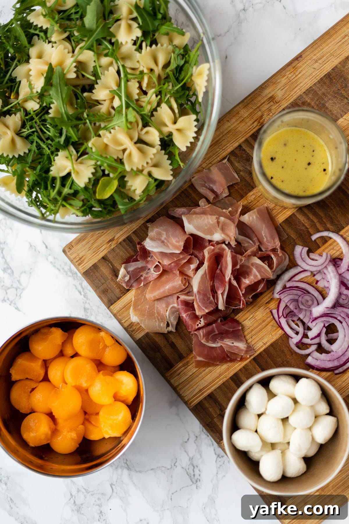 Prosciutto melon pasta salad ingredients laid out on a counter.