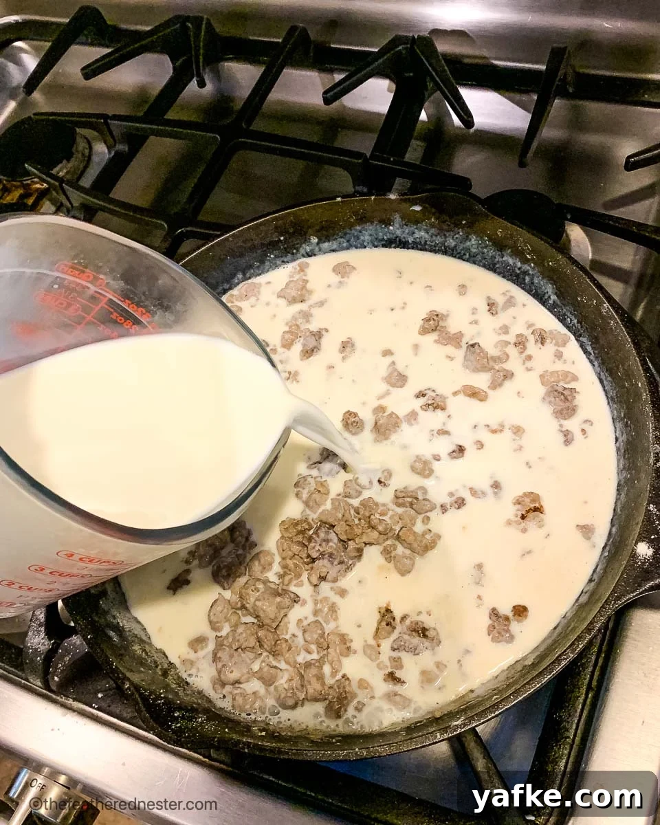 How to Make Homemade Sausage Gravy for Biscuits 4 pouring milk into a cast iron skillet.