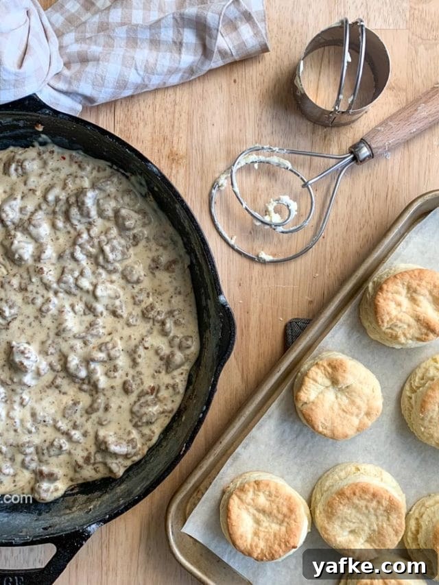 How to Make Homemade Sausage Gravy for Biscuits 6 Sausage gravy in a skillet with baked biscuits and tools.