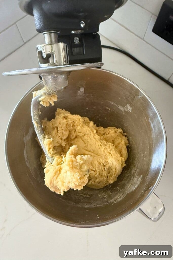 Fluffy Sourdough Discard Honey Butter Dinner Rolls 4 A stainless steel stand mixer bowl with a rough sourdough honey butter roll dough.