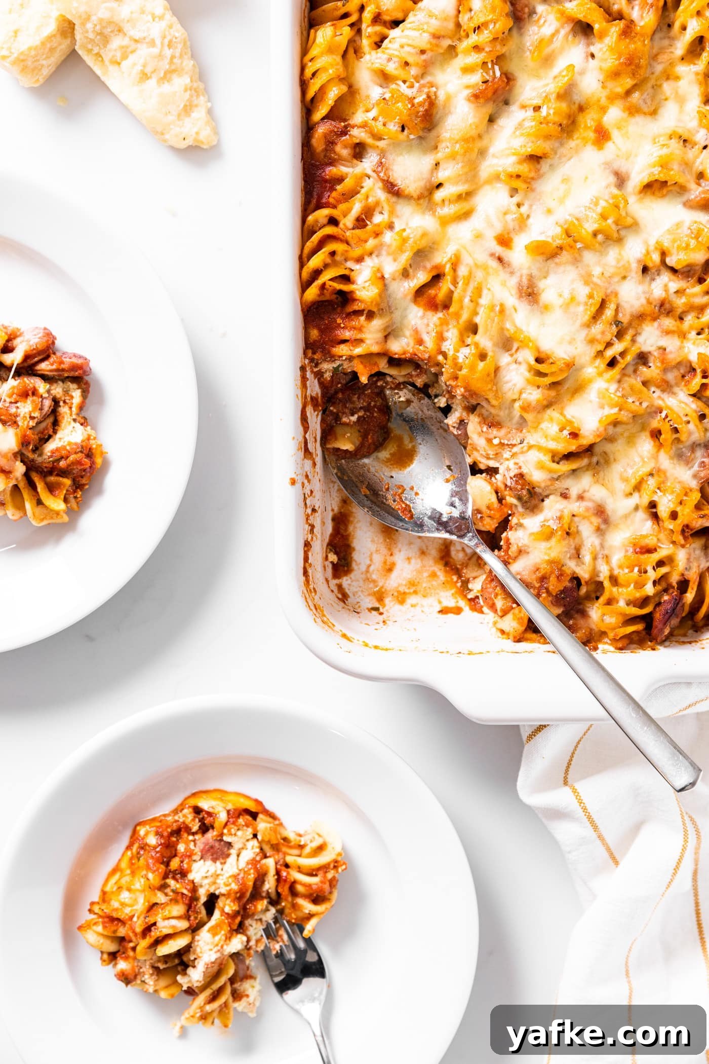 Cheesy Baked Rotini Casserole with Marinara and Mozzarella 4 Top down view of baked rotini casserole sitting on white countertop with scoop sitting on white plate