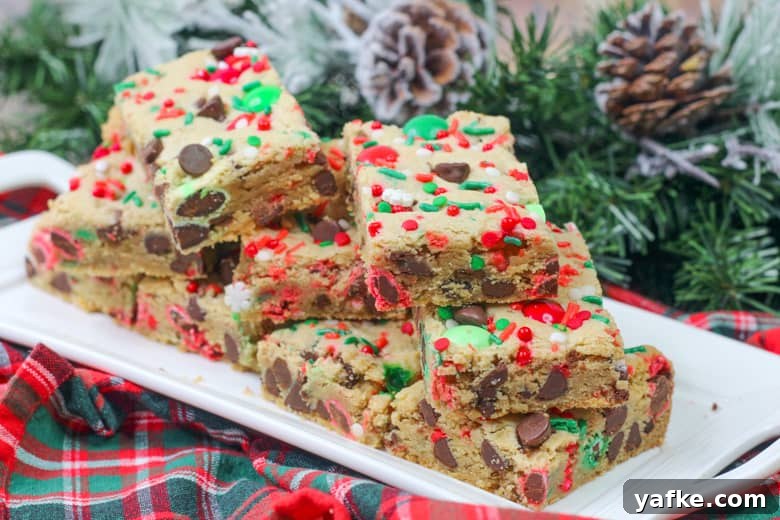 Chewy Christmas Cookie Bars Recipe with Festive Sprinkles 3 Christmas Chocolate Chip Cookie Bars with M&Ms stacked on a plate.